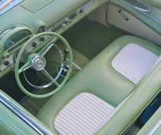 the interior of an old green car with white stitching