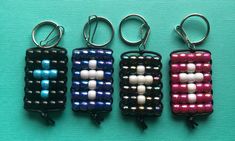 four key chains with beads on them sitting next to each other in front of a blue background