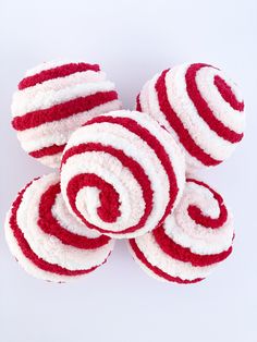 four red and white striped candy rolls on a white surface with one rolled up in the shape of a spiral