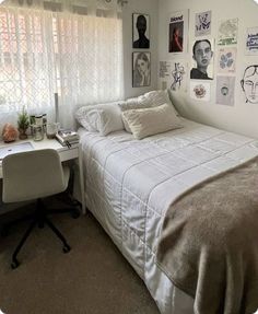 a white bed sitting in a bedroom next to a desk and window with pictures on the wall