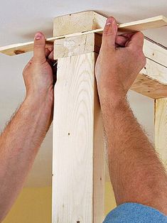 a man is working on the top of a wooden structure with his hands and feet