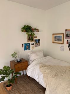 a bed sitting in a bedroom next to a wooden table with a potted plant on top of it