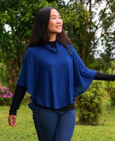 a woman is walking in the grass with her arms spread out and she's wearing a blue top