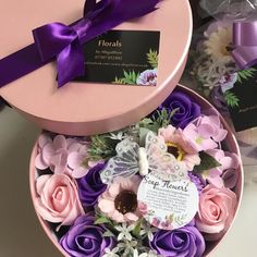 a pink box with purple and white flowers in it next to some other gift items