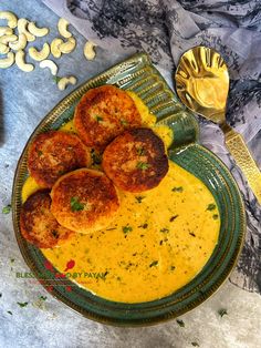 some food is on a green plate with gold spoons and silver utensils