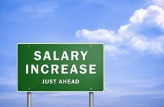 a green highway sign that says,'salary increase just ahead'in front of a blue sky with clouds