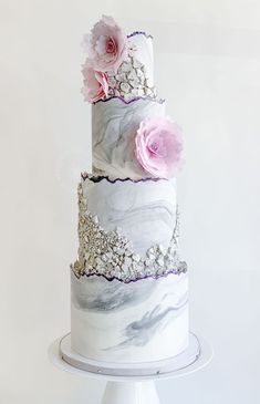 a three tiered marble cake with pink flowers on the top and silver trimmings