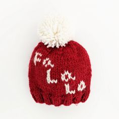 a red knitted hat with white pom - pom on top and the word joy written across it