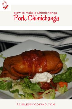 a white plate topped with meat covered in sauce and lettuce next to a salad