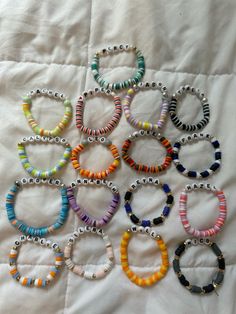 several bracelets are laid out on a white sheet with beaded beads in different colors