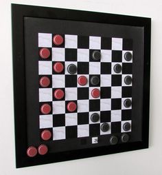 a black and white checkerboard with red buttons on the board is mounted to a wall