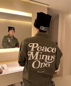 a man is looking at himself in the mirror while wearing a jacket that says peace minus one