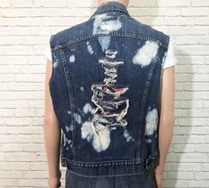 "1980's Levis denim vest. Cut off frayed sleeves with holes and bleach splashes throughout. Non-bulky fit. Dual front chest patch pockets with buttoned flaps. Perfect for adding your own patches + pins to. ✂ Measurements ✂ Labelled size: 45 Fits like: Mens 45 / Medium To Large depending on desired fit // Ladies Large ✂ Measurements: ( taken laying flat and buttoned ) Shoulders: 19.5\" Length: 24.25\" Chest: 22.5\" Waist: 21.25\" Waistband: 20.5\" Label + Fabric Levis Made in U.S.A 100% Cotton Co Grunge Sleeveless Vest For Spring, Sleeveless Grunge Vest For Spring, Spring Sleeveless Grunge Vest, Spring Grunge Sleeveless Vest, Fitted Grunge Vest For Festivals, Distressed Fitted Denim Vest For Summer, Distressed Denim Sleeveless Vest For Fall, Fitted Distressed Denim Vest For Summer, Distressed Sleeveless Denim Vest For Fall