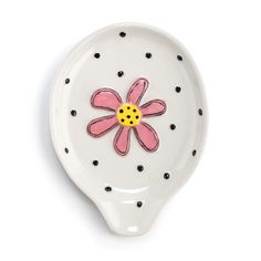 a white plate with a pink flower painted on the side and black dots around it