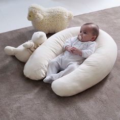 a baby is laying on the floor next to stuffed animals