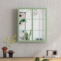 a green window frame on the wall above a table with potted plants and books