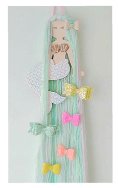 a wall hanging with some hair clips attached to it's sides and an image of a mermaid in the background