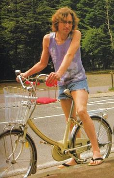 a woman riding a bike on the side of a road with trees in the background