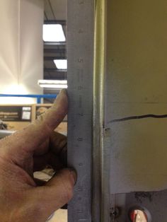 a person is holding up a ruler to measure the height of a building's wall