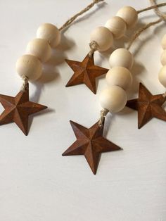 three wooden stars are hanging from string on a white surface with twine and wood beads