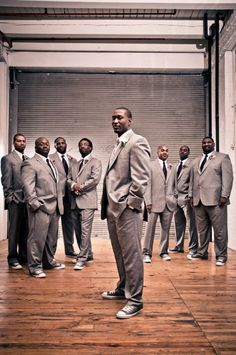 a man standing in front of a group of other men wearing grey suits and ties