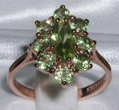 "*This flower ring is made from 375 9K (9ct 9Kt) Rose Gold with Genuine Natural Semi-precious Peridot. Like all my jewelry pieces, this ring is made in my own workshop.  PLEASE MAKE SURE YOU STATE THE FINGER SIZE YOU REQUIRE WITH YOUR PAYMENT AND ALSO INCLUDE YOUR TELEPHONE NUMBER FOR DELIVERY COURIER. This Delightful Solid 9K Rose Gold Ring has been hand set with a large Marquise Peridot 8x4 mm (0.32\" x 0.16\") and eight 3.25mm (0.13\") matching Peridots, in a simple cluster arrangement. These are Genuine Natural Peridots. They have such an eye catching green color and contrast with the Polished Rose Gold beautifully. The Gold is Solid 9K Rose Gold authenticated by the Assay Office in London, England. They have stamped there mark on the inside of the shank to confirm that this ring is ma Luxury Green Flower Ring For Anniversary, Elegant Luxury Green Flower Ring, Luxury Vintage Green Cluster Ring, Peridot Engagement Ring, Peridot Engagement Rings, English Vintage, Floral Ring, Flower Ring, Pink Tourmaline