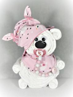 a white teddy bear with a pink hat and scarf on it's head sitting in front of a gray background