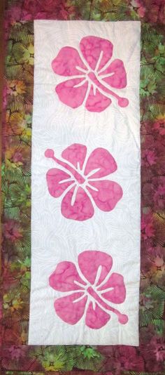 a quilted wall hanging with pink flowers on it