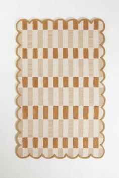 a brown and white checkered rug with scalloped edges on a white wall