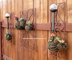 some plants are hanging on the side of a wooden fence with metal brackets and lights