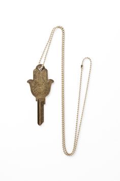 a gold necklace with a hamsa hanging from it's side and a key to the other side