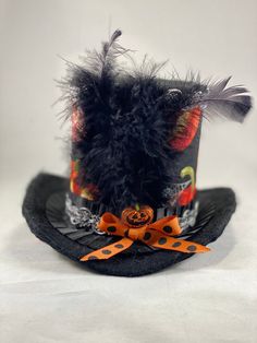 Lightweight and very easy to wear, it can easily be positioned and secured at the appropriate angle, with two alligator clips, hidden from sight. Brim made with fabric and wire so its easy to bend to adjust to head. This mini hat is 3 1/2 inches tall. Perfect hat to complete your Halloween look! This hat is ready to ship only in the U.S. because of the feathers. Please contact me with any questions you might have. Follow me on Facebook and Instagram. https://www.facebook.com/EleyasDesigns/ https Novelty Brimmed Mini Hats For Costume, Novelty Brimmed Mini Hat For Costumes, Adjustable Black Top Hat As A Gift, Adjustable Black Top Hat Gift, Novelty Black Brimmed Mini Hats, Themed Adjustable Top Hat With Curved Brim, Halloween Adjustable Top Hat With Short Brim, Halloween Top Hat With Short Brim, Adjustable Mini Hats With Short Brim For Halloween