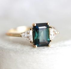 Trina Bicolor Sapphire Ring With Side Trillion Diamonds – Capucinne Sapphire Proposal Ring, Teal Sapphire Engagement Ring, Engagement Ring Emerald Cut, Ring Stones, Trillion Diamonds, Engagement Ring Emerald, Green Sapphire Ring, Ring Emerald Cut, Triangle Diamond