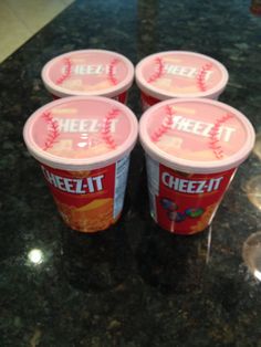 four ice cream cups with baseballs on them sitting on a counter top next to each other