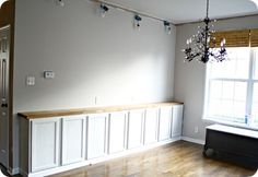 an empty room with white cabinets and a chandelier