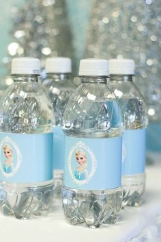 three water bottles with labels on them sitting on a table next to silver sequins