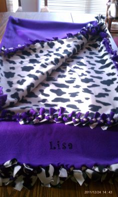 a purple and white blanket on top of a table with the name lisa written on it