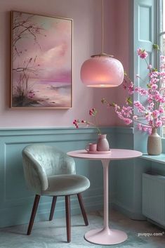 two chairs and a table with pink flowers in vases next to a painting on the wall