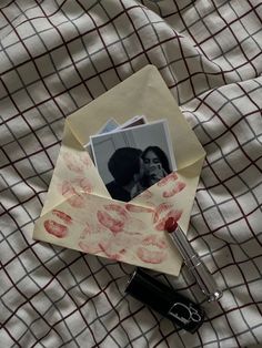 an origami photo and lipstick on top of a sheet of paper next to a pen