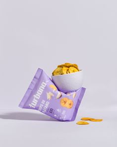 a purple bag filled with gold coins next to a white bowl full of golden chips