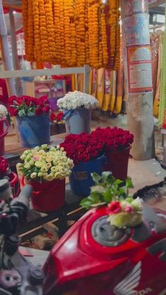 many flowers are sitting in buckets on the table next to each other and hanging from the ceiling