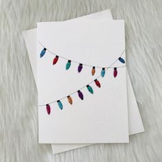 two cards with colorful feathers hanging from them