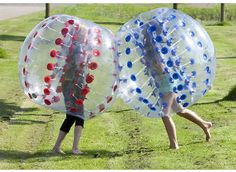 two people are playing with inflatable balls on the grass