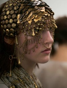 a close up of a woman with gold jewelry on her face and headdress