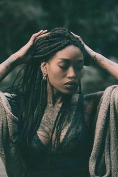 a woman with dreadlocks and tattoos on her chest is posing for the camera