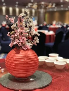 a vase filled with flowers sitting on top of a red table cloth covered round plate