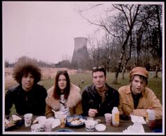 three people sitting at a table with food and drinks in front of a cooling tower