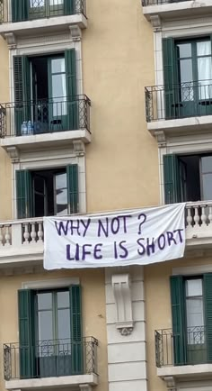 a banner that says why not? life is short hanging from the side of a building