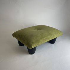 a green ottoman sitting on top of a white floor