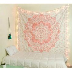 a white bed topped with a pink and white blanket next to a wall mounted light